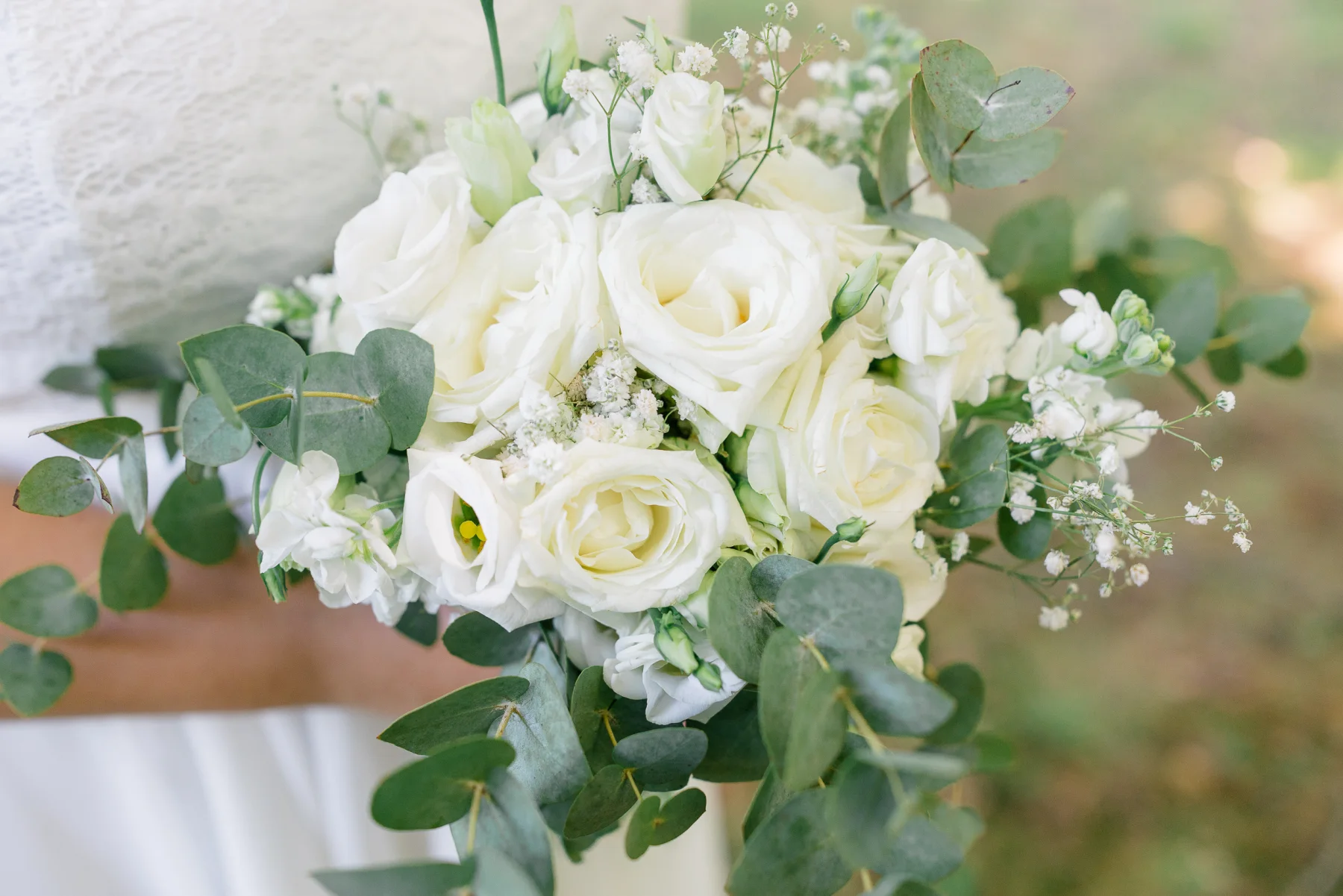 Ein Brautstrauß aus weißen Rosen und grünen Blättern.